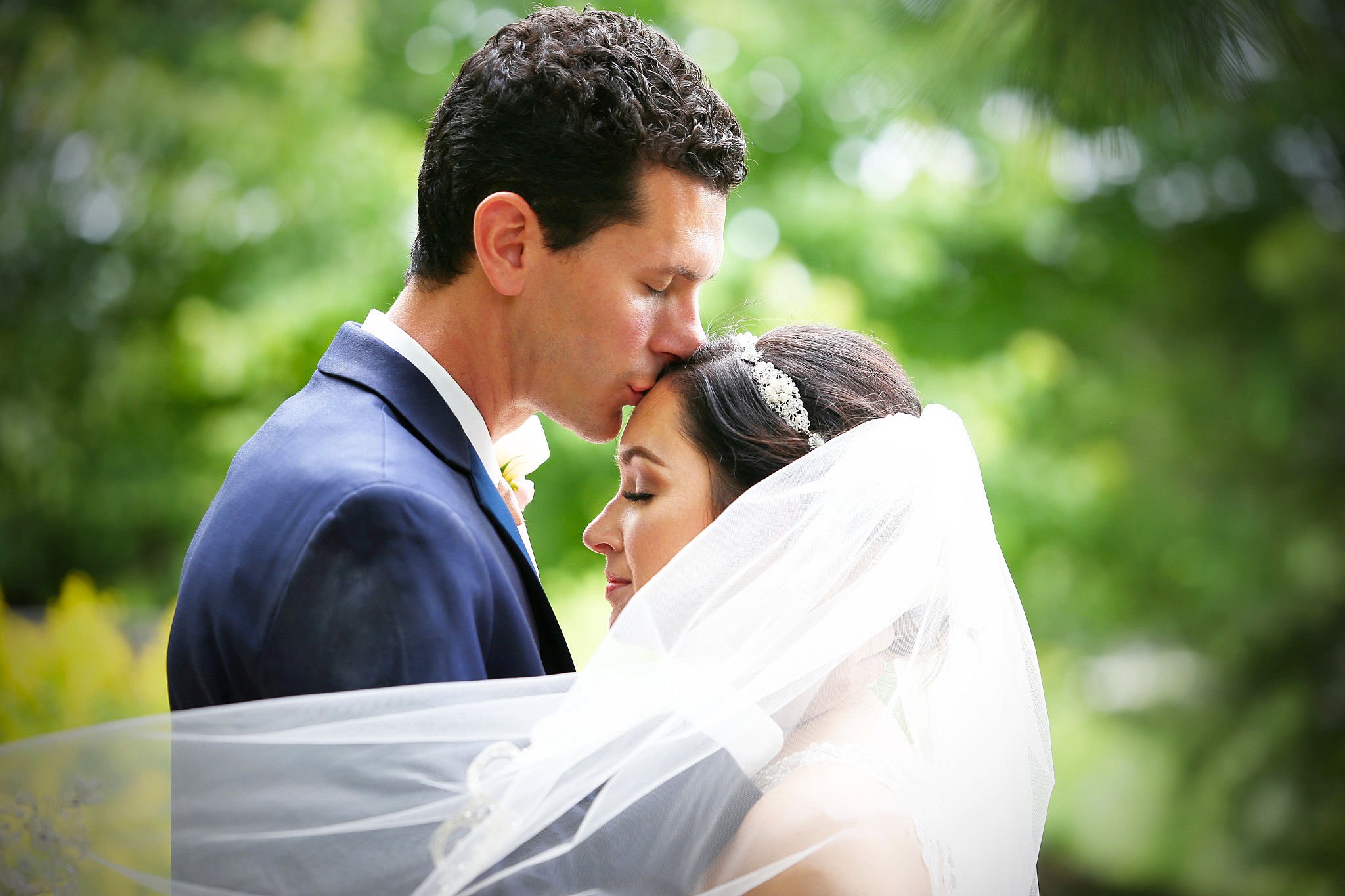 Groom kissing bride on forehead